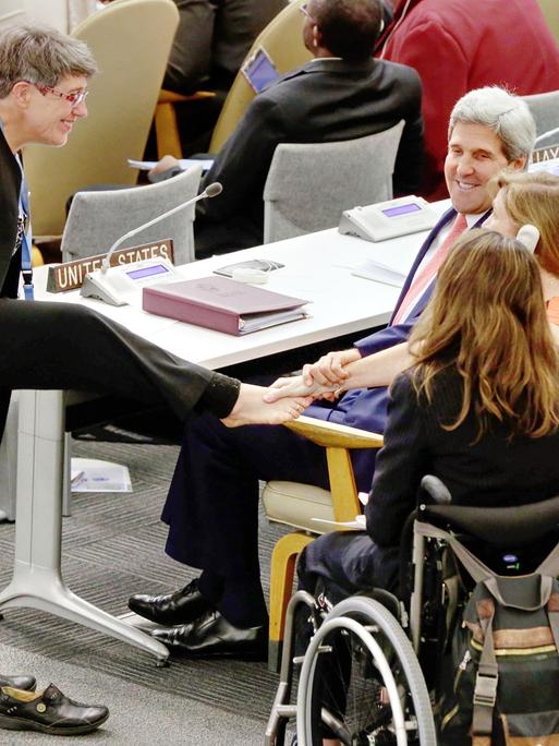 Theresia Degener (links) begrüsst den damaligen U.S. Secretary of State John Kerry und die U.S. Botschafterin bei den Vereinten Nationen Samantha Power mit ihrem rechten Fuß. 