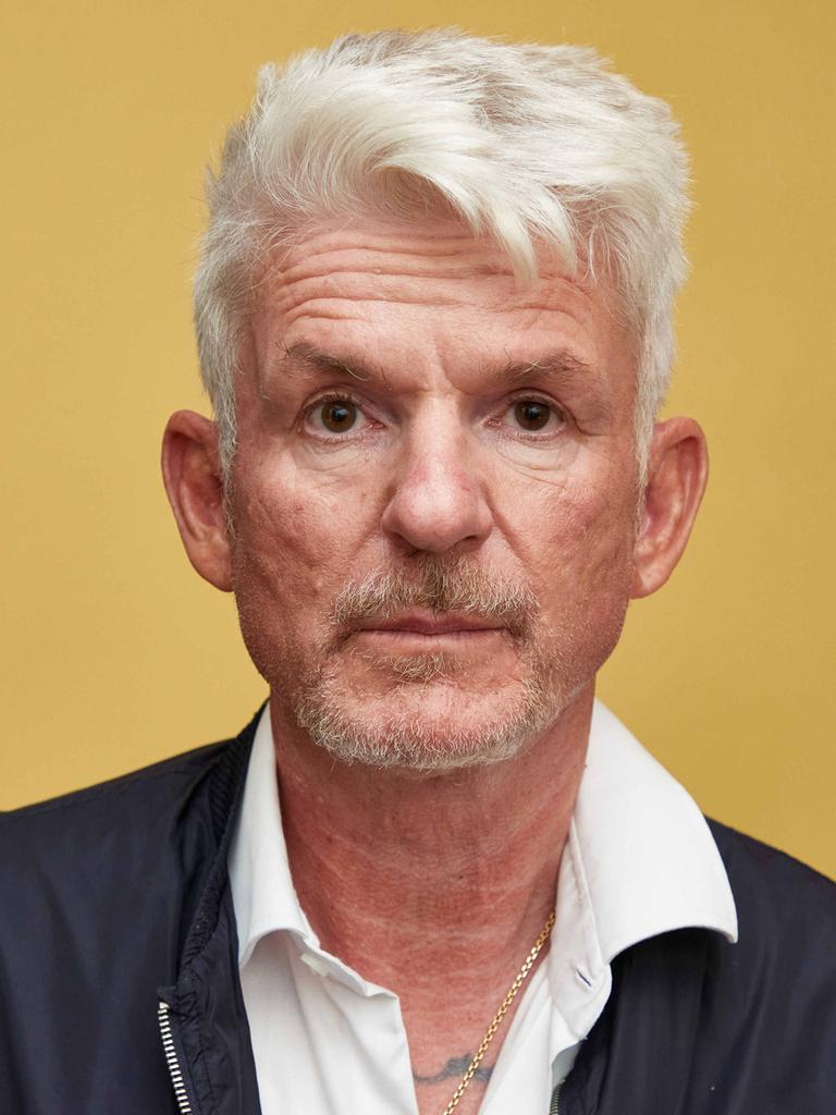 Der Schriftsteller Heinz Strunk blickt vor gelbem Hintergrund ernst in die Kamera