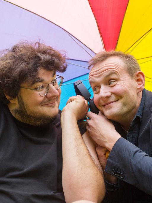 Axel Rahnisch und Devid Striesow unter einem regenbogenfarbenen Schirm