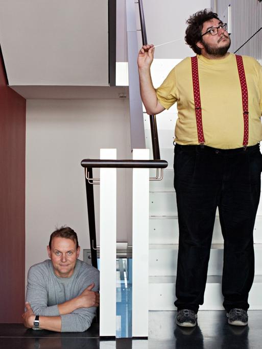 Devid Striesow und Axel Ranisch stehen im Treppenhaus von Deutschlandfunk Kultur.