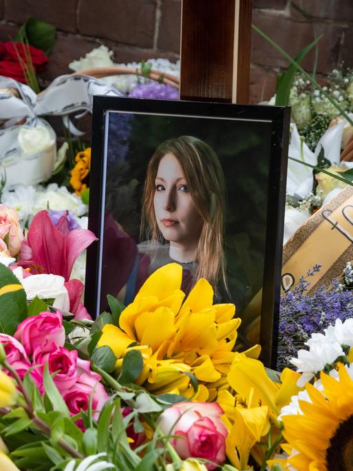 Ein von Blumen umgebendes Foto von Victoria Amelina in einer Kirche bei der Trauerfeier für die verstorbene Schriftstellerin