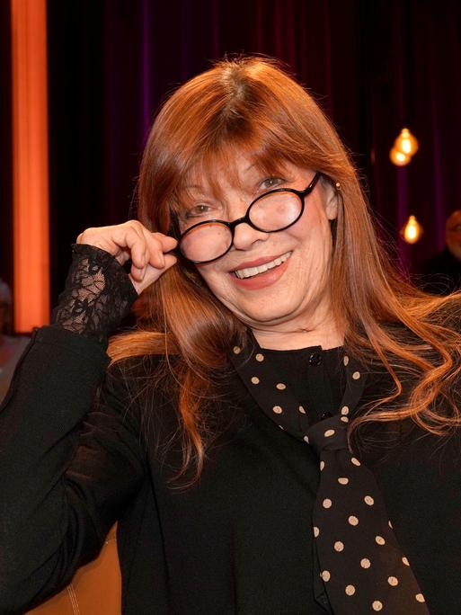 Die Sängerin und Schauspielerin Katja Ebstein schaut über den Rand ihrer Brille und lächelt in die Kamera.