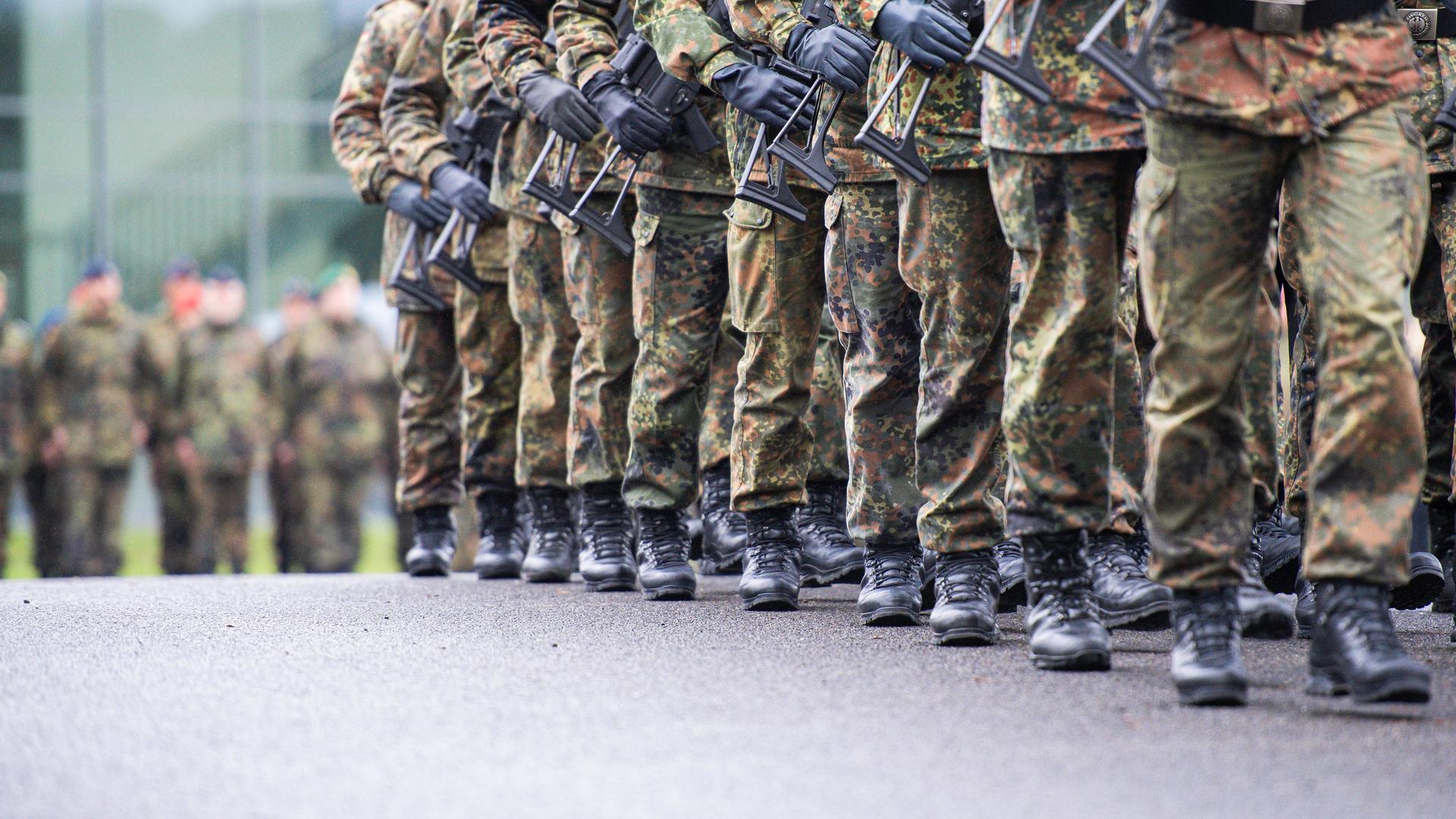 Soldaten marschieren mit Gewehr in Reih und Glied