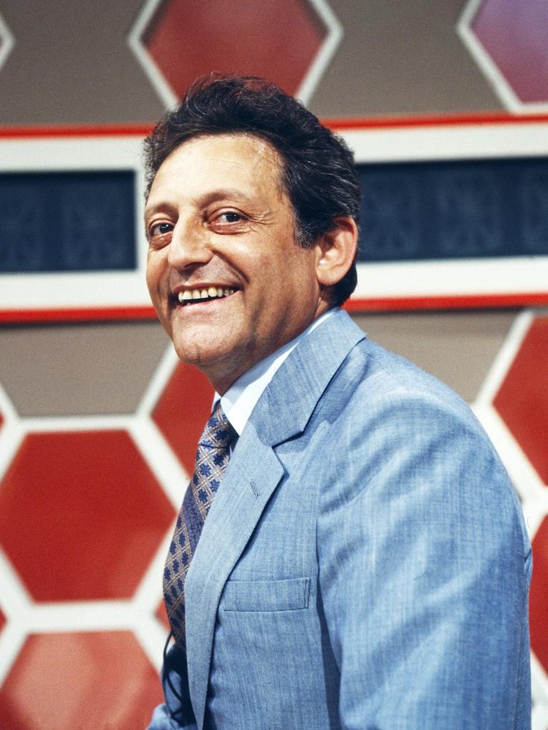 Hans Rosenthal steht vor dem typischen Waben-Hintergrund im Studio seiner Sendung "Dalli Dalli" und lacht in die Kamera