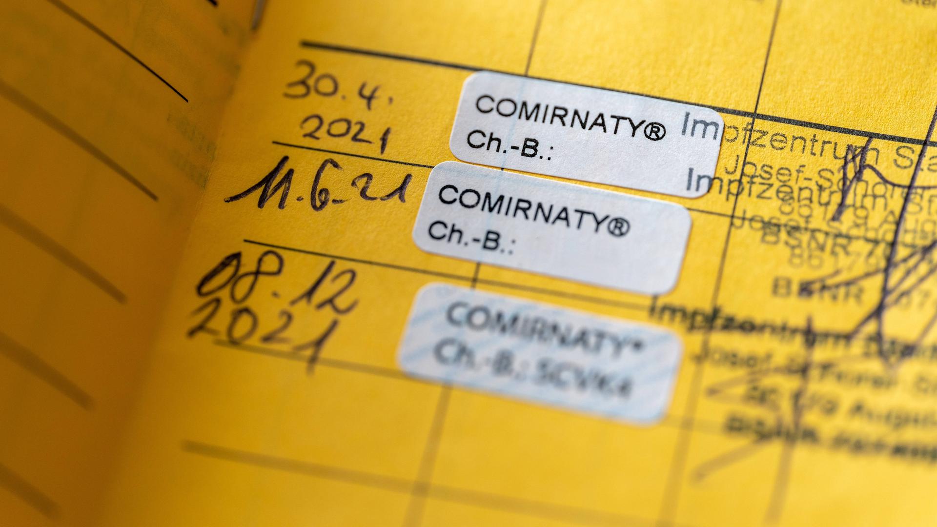 Drei Einträge von Covid-Impfungen in einem gelben Impfpass
